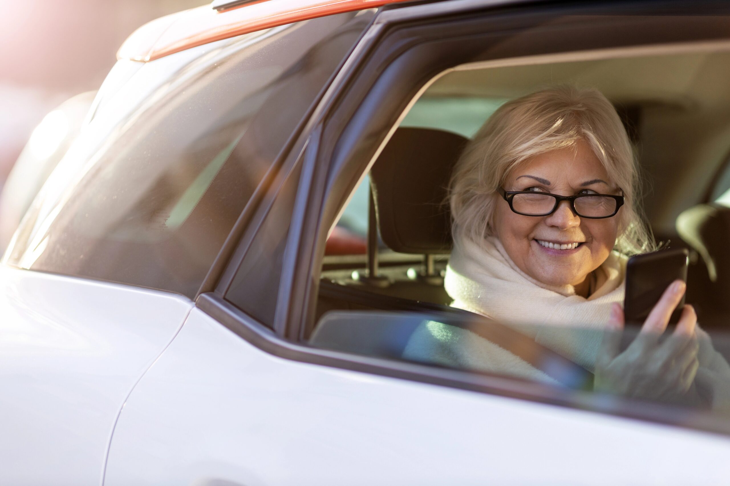 old woman inside a car using her phone
