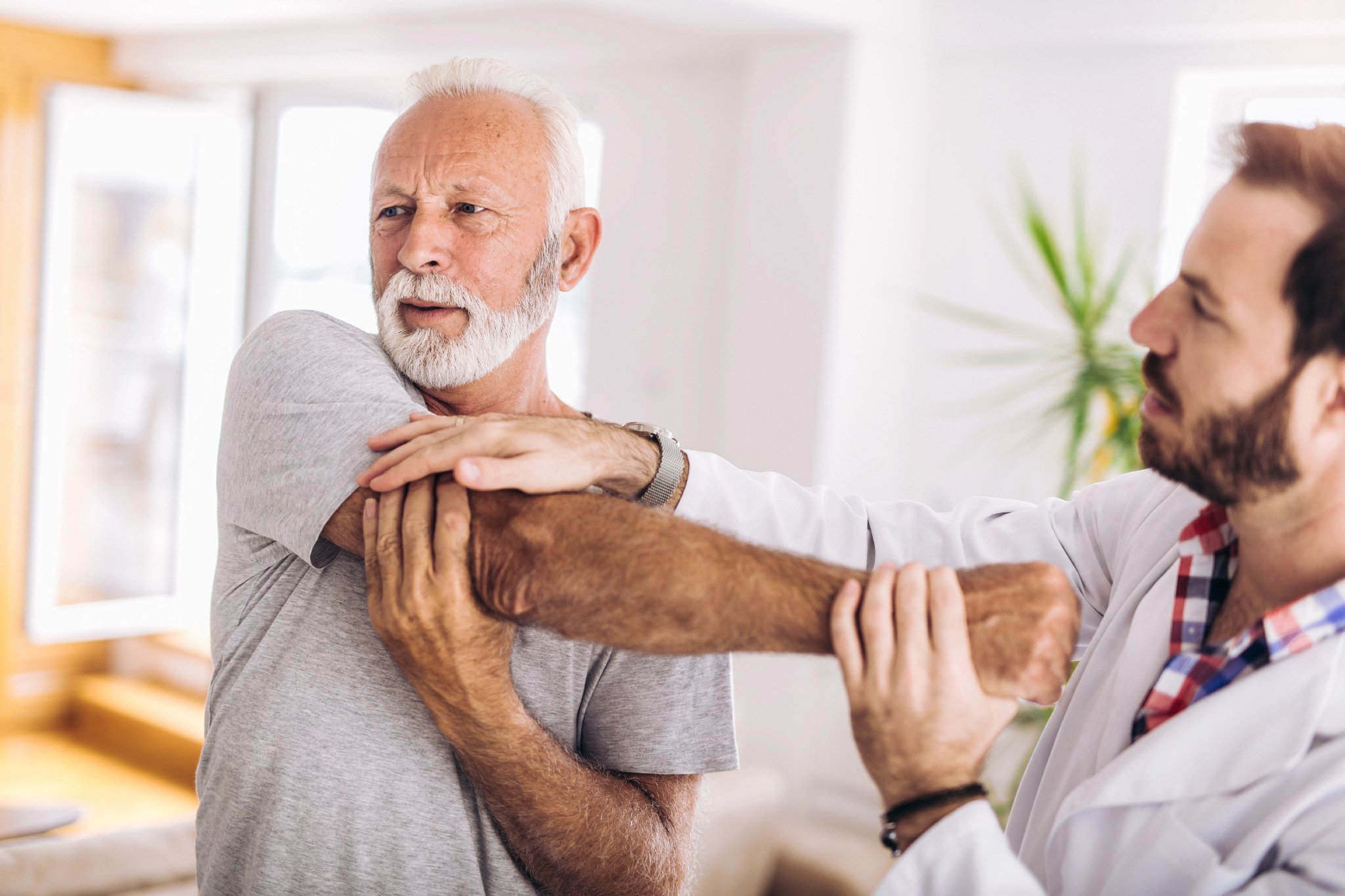 care giver helping an old man stretch his arm