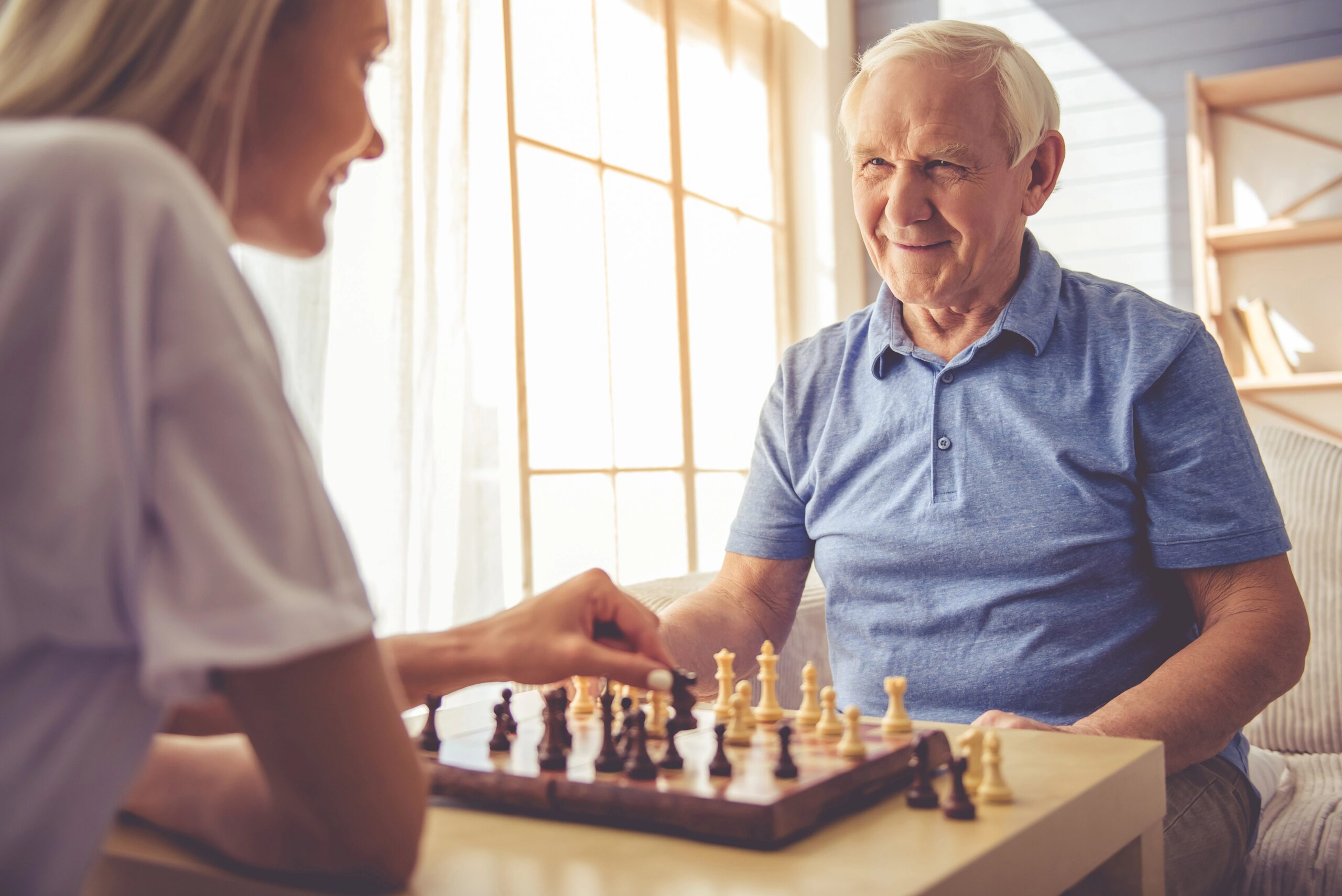 old man playing chess with his daughter